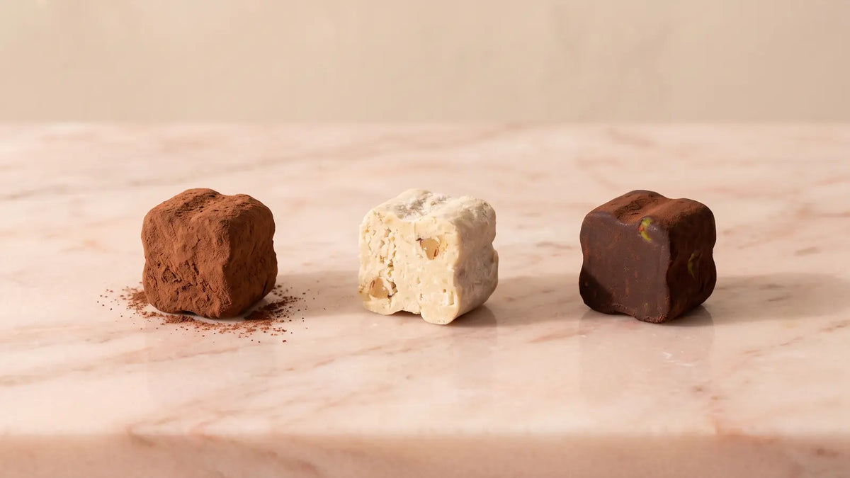 Drei unverpackte Tartufi dolci – klassisch mit Kakao, Kokos und Himbeere-Pistazie – auf rosa Marmor